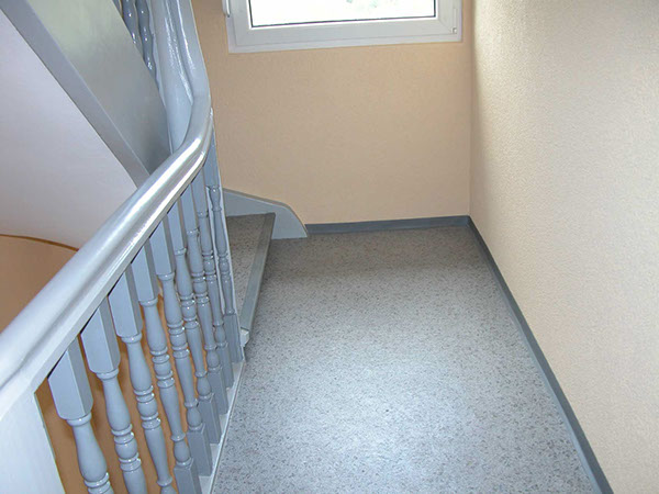 Neu verlegter Bodenbelag und lackiertes Geländer in einem hellen Treppenhaus